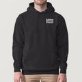 A man wearing a black pullover hoodie with white text on the left chest that reads 'SAEYY SPROCKET'. The background is a solid light gray studio backdrop.